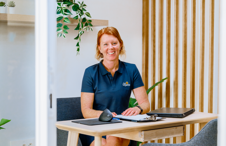 Emma Gibbins posing for a phoyo sat behind a wooden desk in her office.