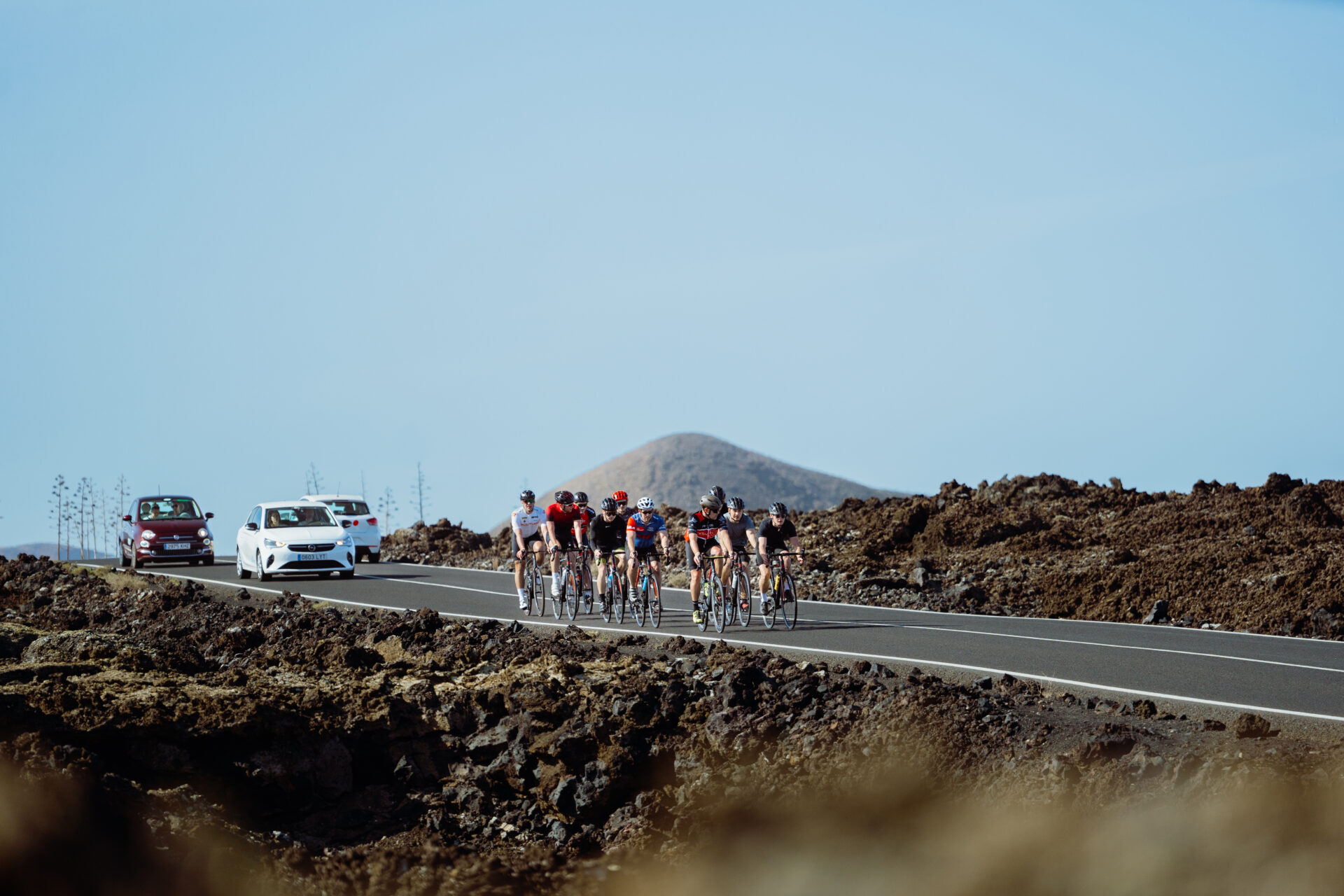 A road in Lanzarote with cyclist on and cars following behind.