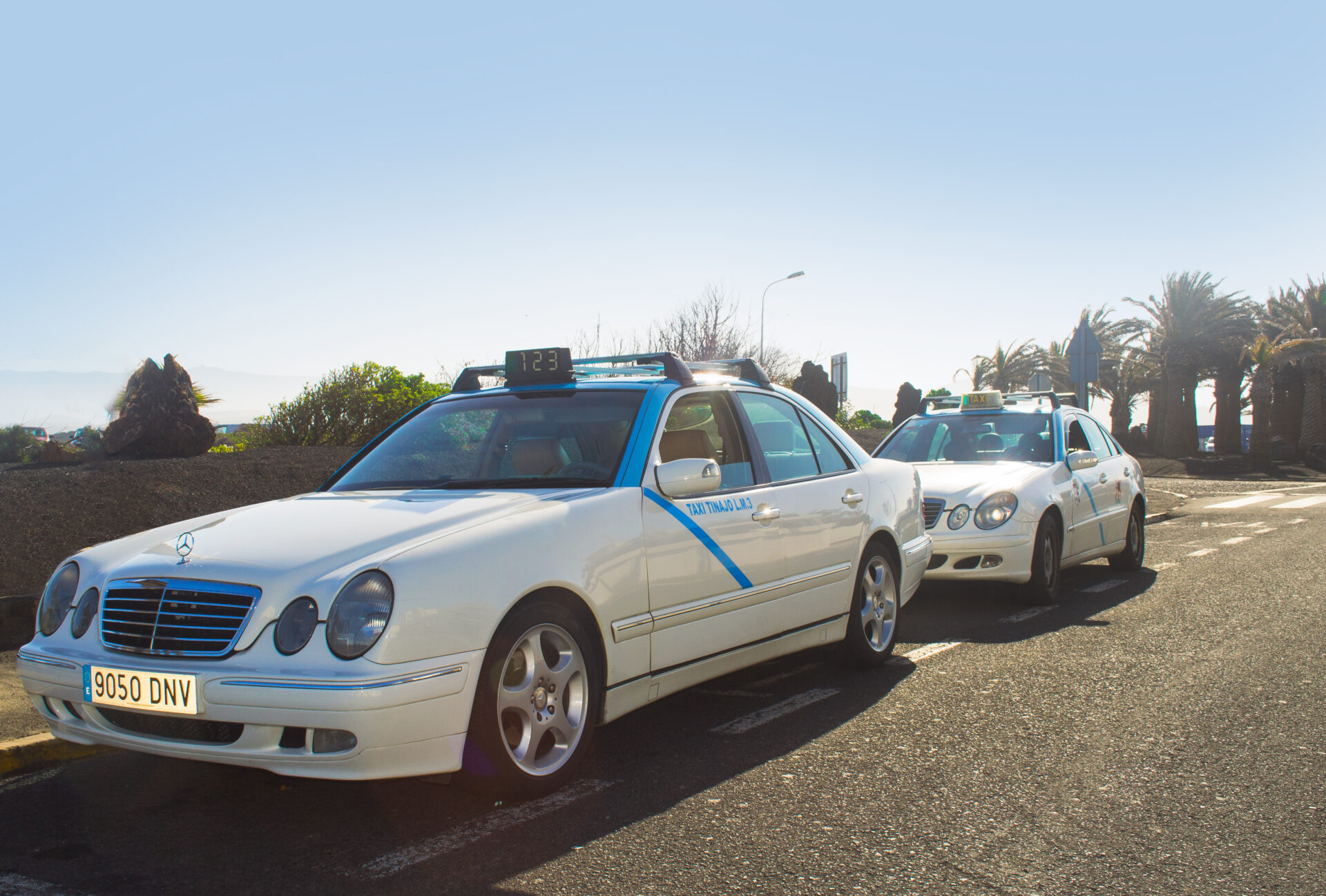Two taxi cars driving down a road in Lanzarote.